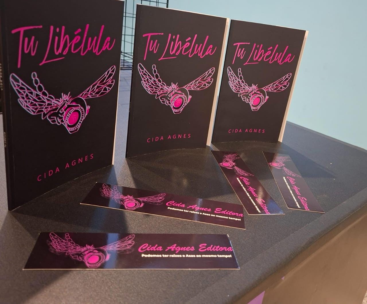 Exemplares do livro Tu Libélula em exposição com marcadores da Editora Cida Agnes